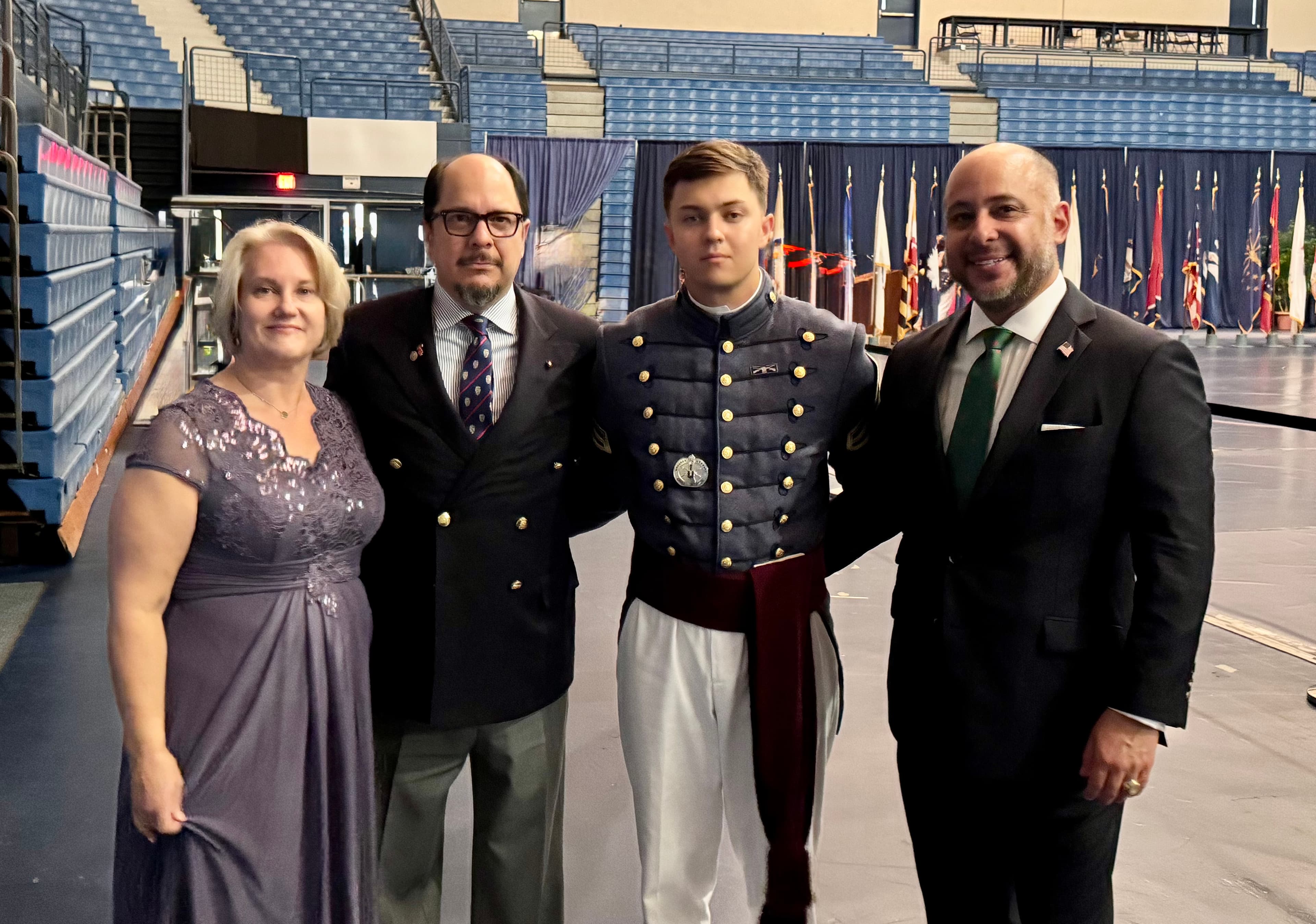 A cadet and family pose together on the floor of McAlister Field House after the ring walk at The Citadel.