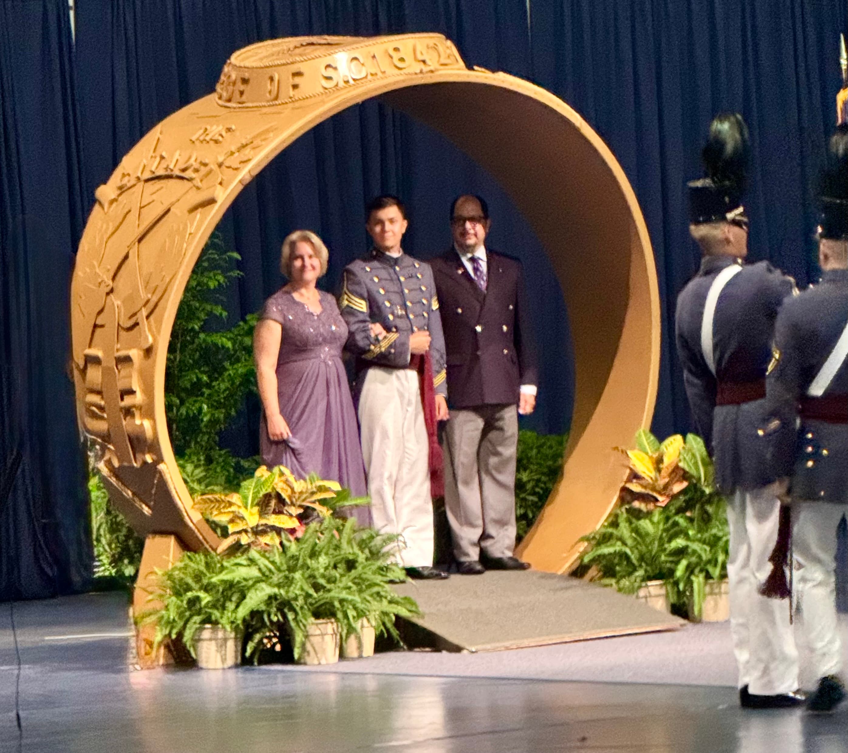 A cadet and family step through the gold Class of 1842 ring arch during the ring walk at McAlister Field House.
