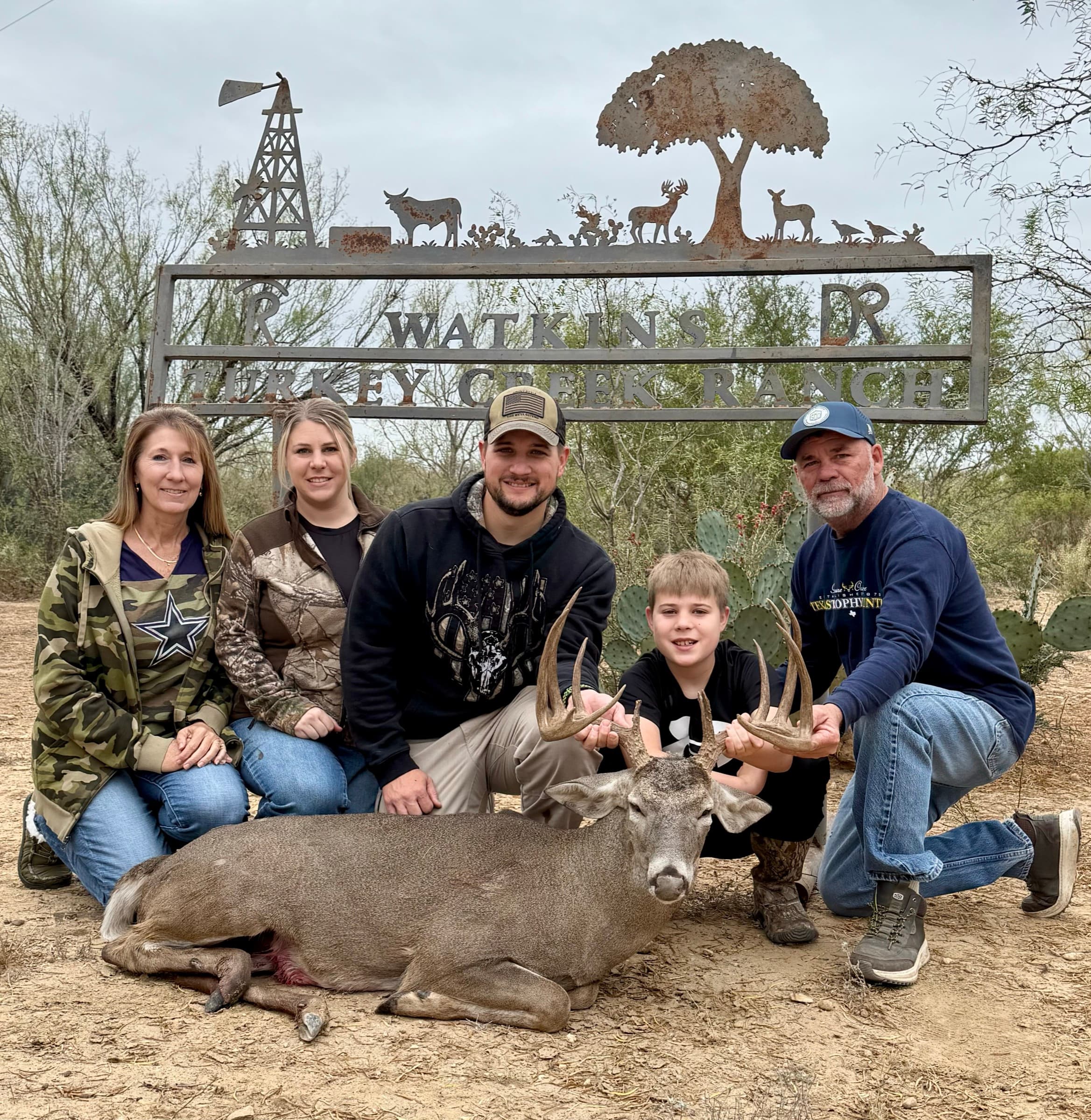 A harvested whitetail buck displayed at the WS Turkey Creek Ranch entrance sign after a successful hunt.