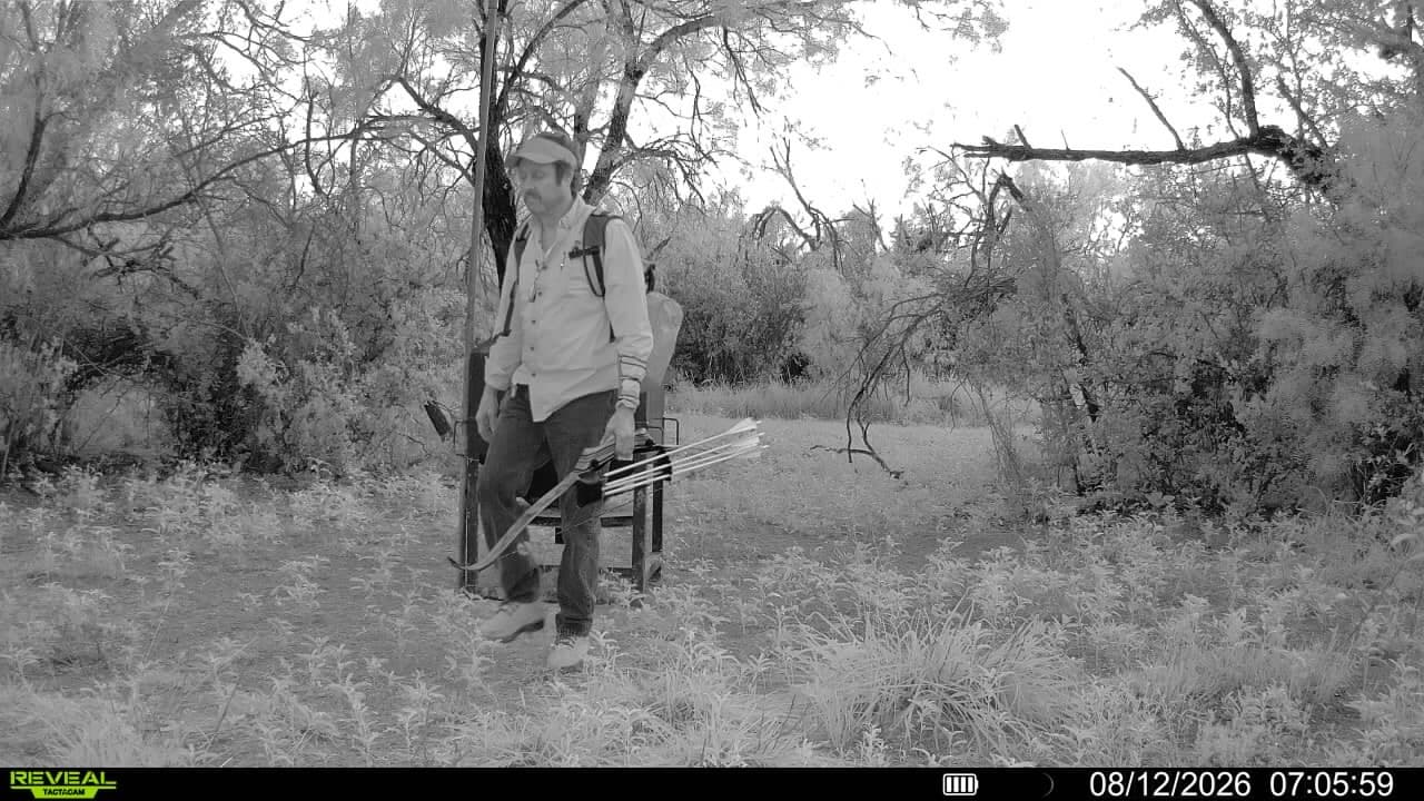 A trail camera captures a hunter walking out across a field with a crossbow at Brochin Expeditions.