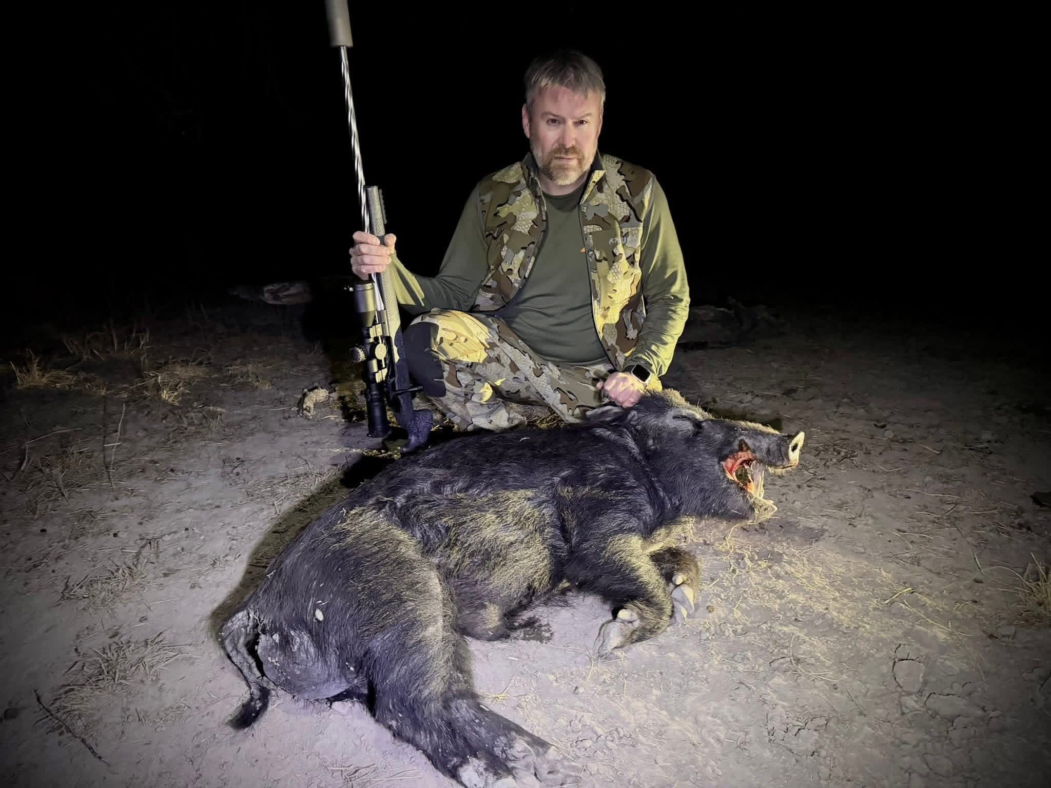 A hunter poses with a harvested wild hog after a night hunt at Brochin Expeditions.