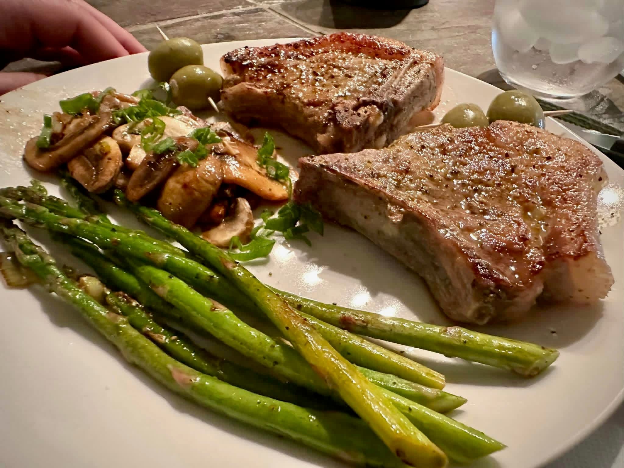 A plated meal of seared pork chops, mushrooms, asparagus, and olives served at Brochin Expeditions.