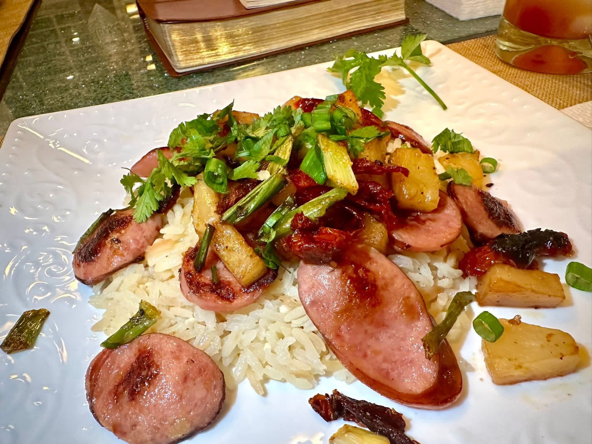 A plate of sliced grilled sausage over rice with pineapple and herbs at Brochin Expeditions.