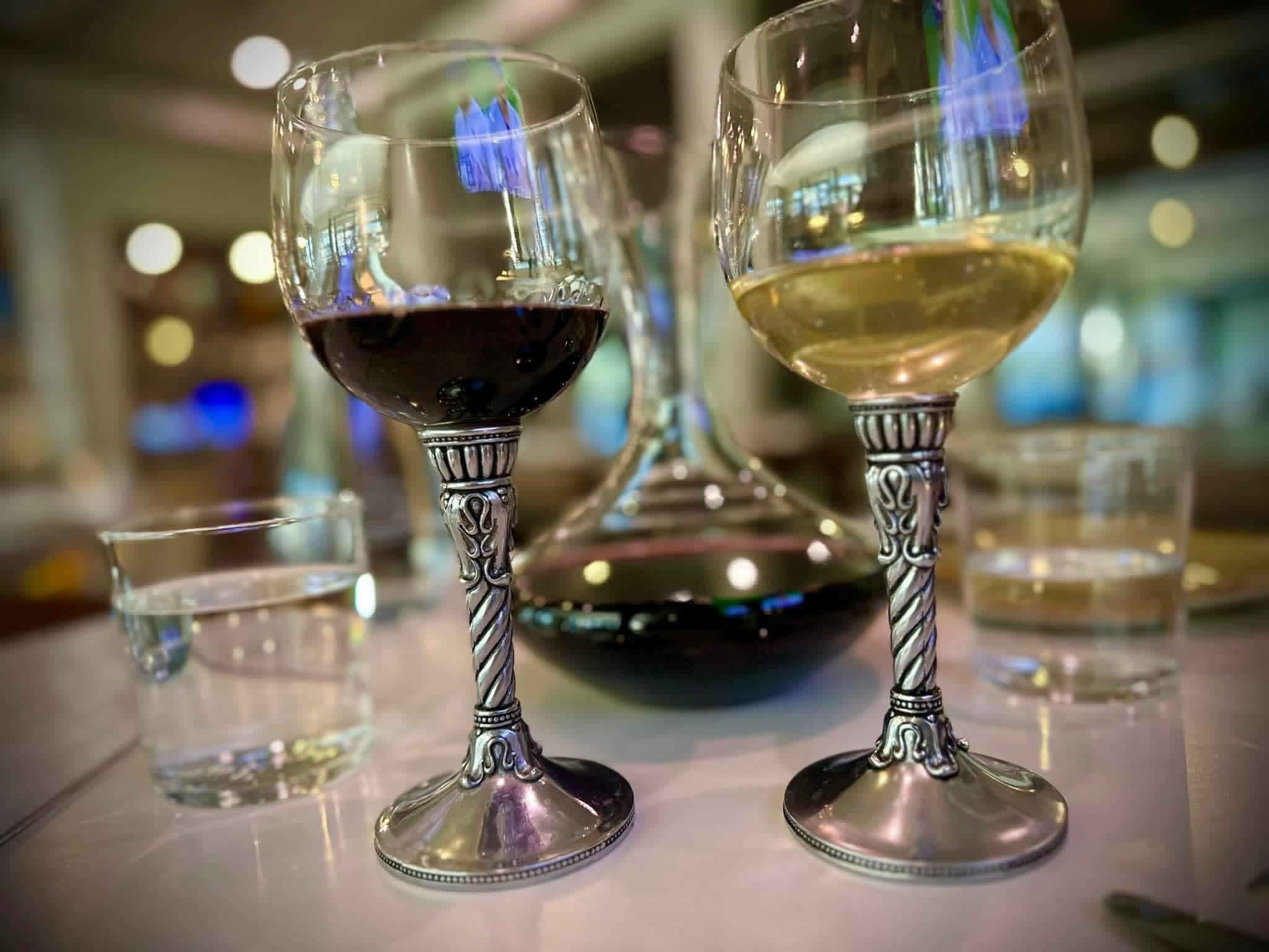 Two silver-stemmed wine glasses with red and white wine beside a decanter on the lodge dining table at Brochin Expeditions.